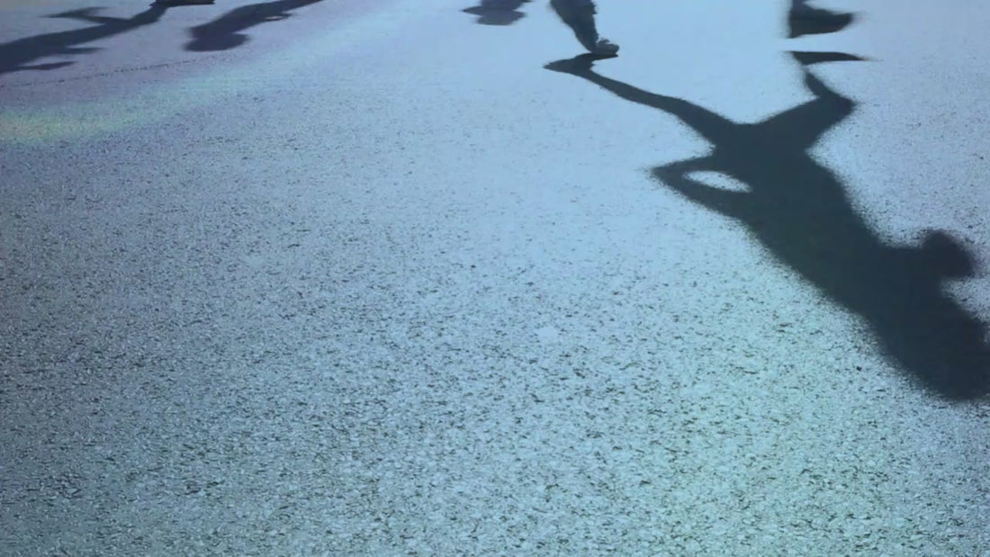 The legs/feet of people running from left to right on pavement.